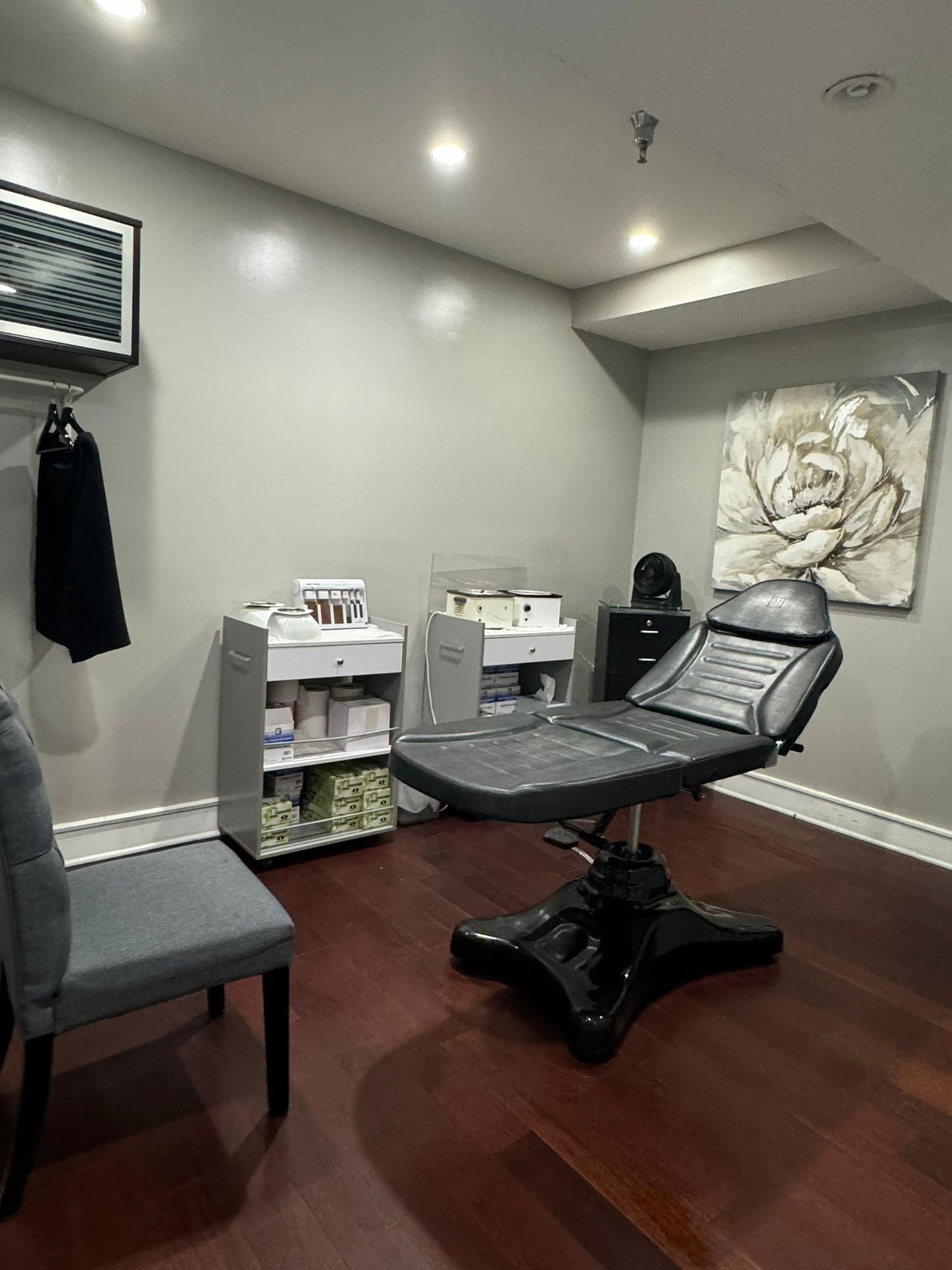 Empty spa or tattoo parlor room with a leather reclining chair and wooden floor.