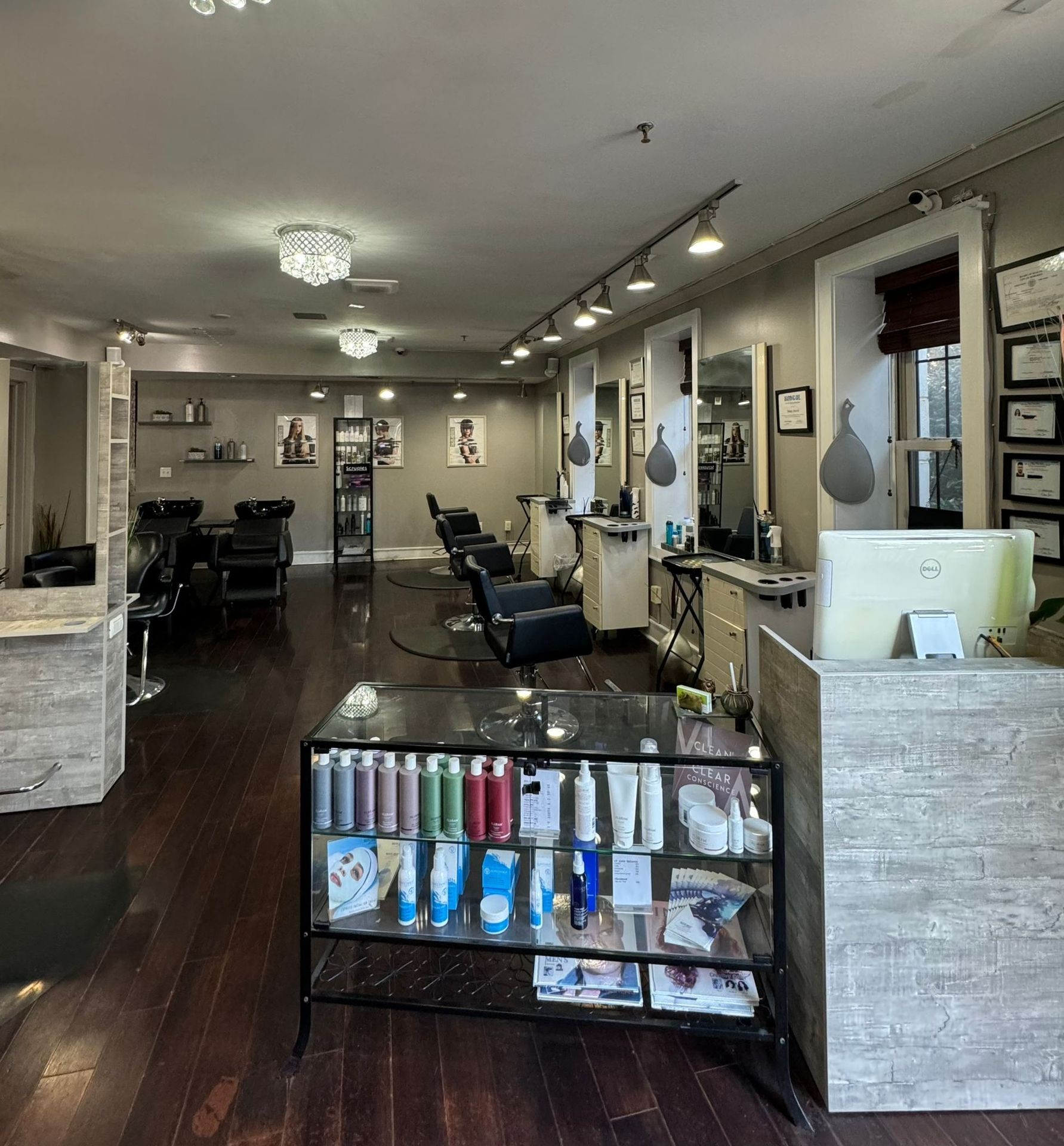 Interior of a modern hair salon with styling stations, chairs, and product shelving.