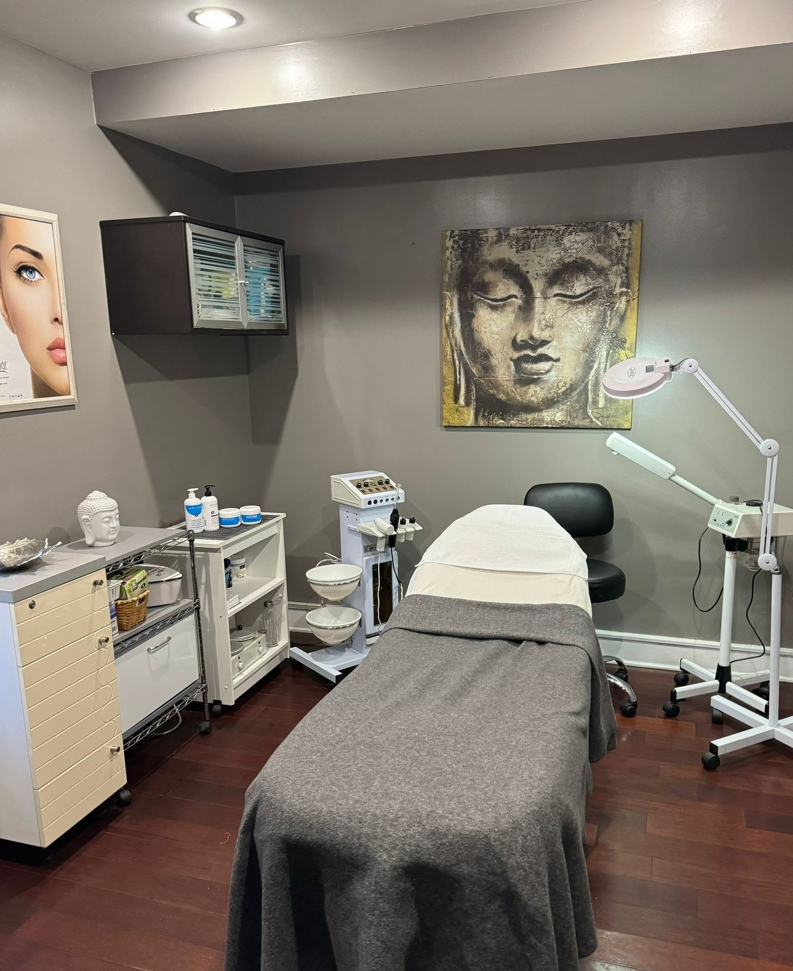 Aesthetic treatment room with a massage table, skincare products, and Buddha-themed decor.