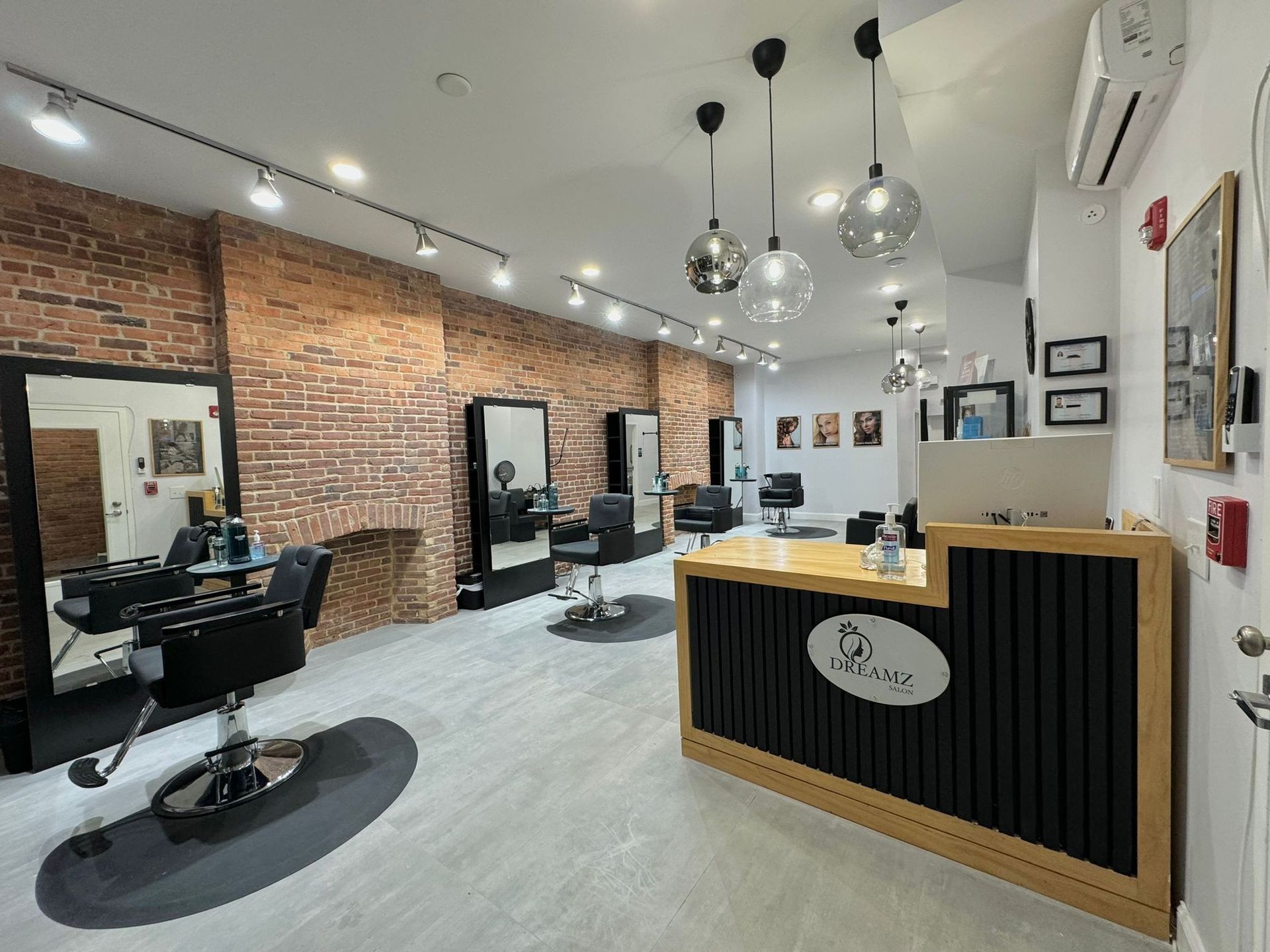 Modern salon interior with styling chairs, mirrors, and a brick wall backdrop.